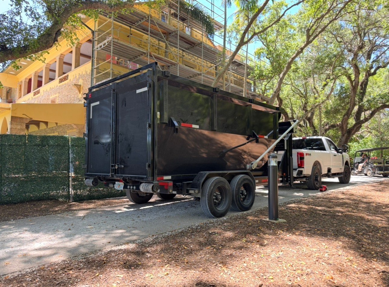 Construction dumpster rental Miami — Barraza Industries roll-off bin and Ford F-350 on luxury home construction site with scaffolding