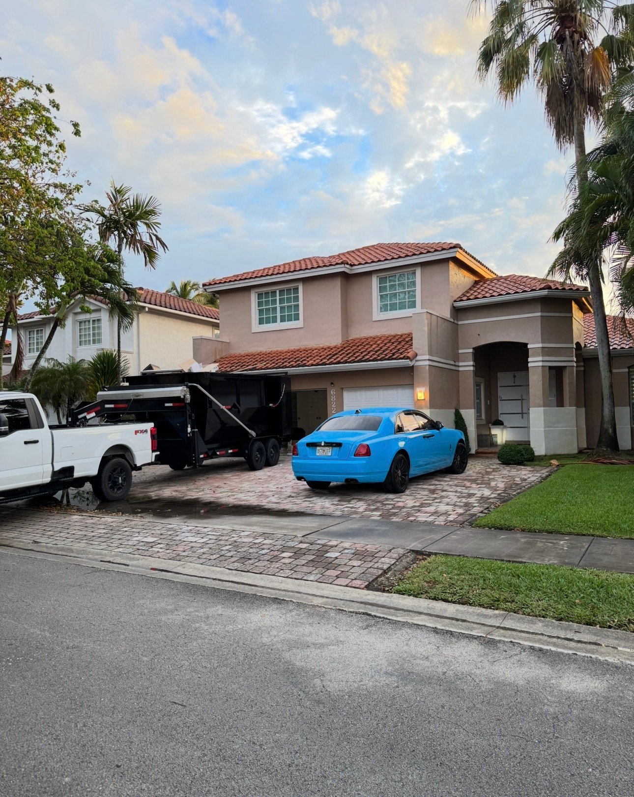 Luxury home dumpster rental Miami — Barraza Industries Ford F-350 and roll-off dumpster trailer at Gables Estates property