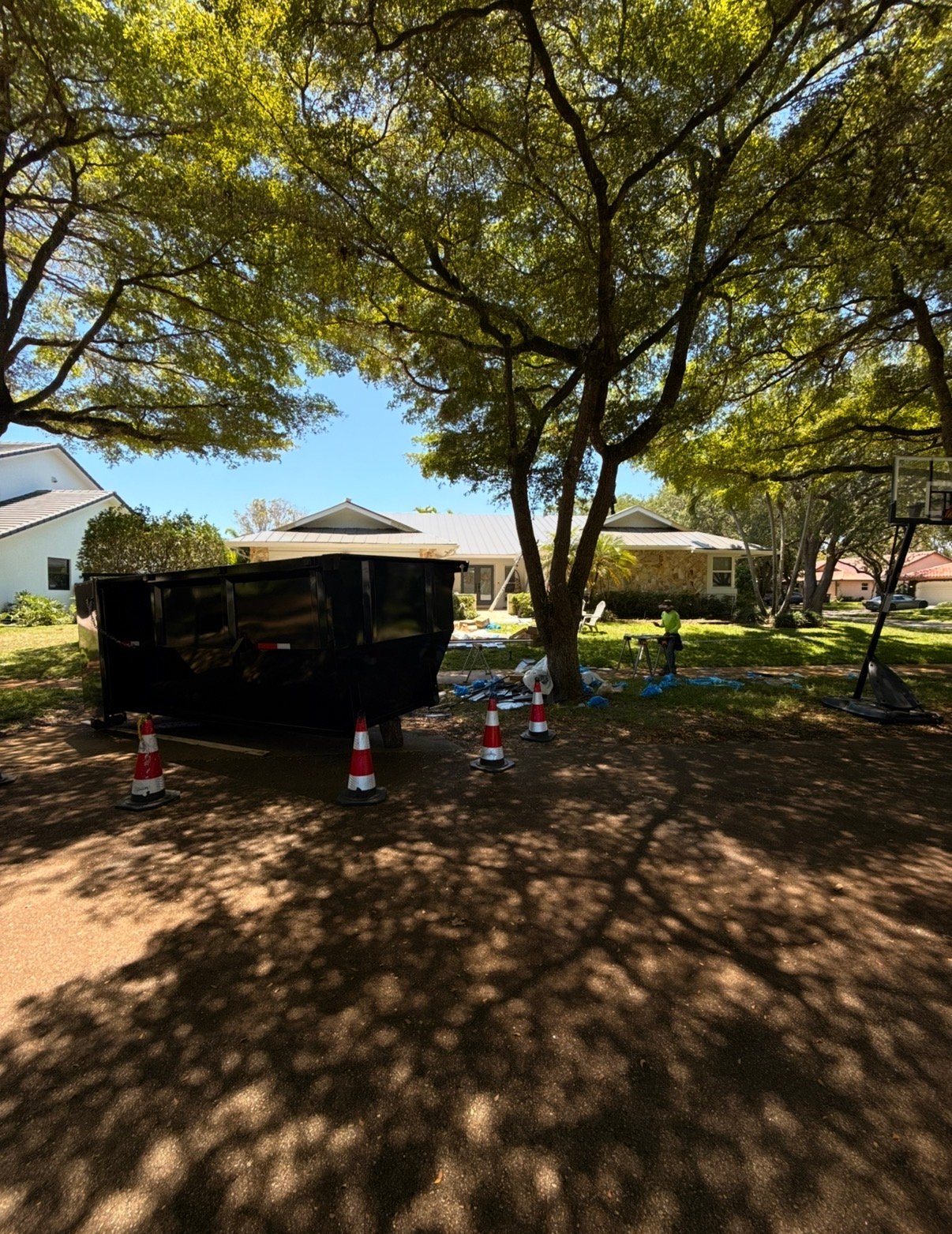Residential dumpster rental Coral Gables Miami — Barraza Industries roll-off bin and working crew on shaded driveway
